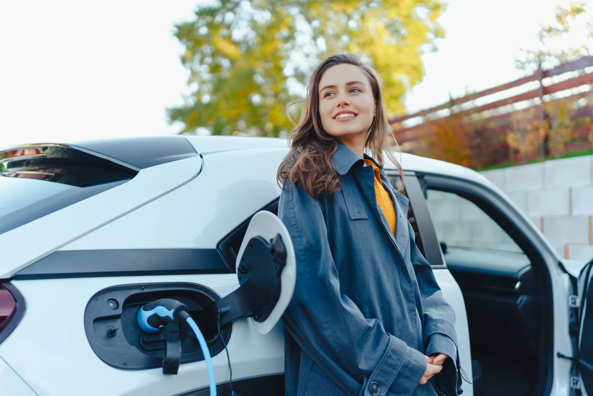 Hopeful woman standing near electric car.